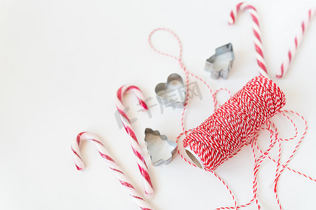 礼物曲奇摄影照片_白色桌子上放着圣诞糖果，还有曲奇模具、用于包装礼物的红线。 
