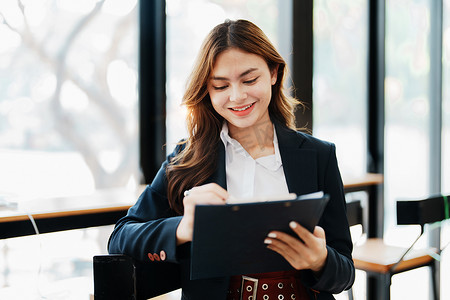 美丽的年轻亚洲女商人的肖像在会议上向同事展示业务利润,并使用平板
