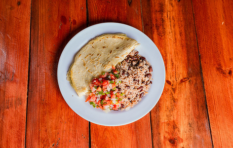 Quesillo 菜与 gallo pinto 和 pico de gallo 在木桌上。