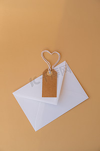 样机纸质摄影照片_白色信封，米色纸条和心形绳索，背景为中性米色。