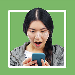 边框手机摄影照片_亚洲女人，哇，手机上有绿色背景的边框，看着移动文本。