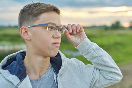 14 岁男孩戴眼镜的特写室外肖像