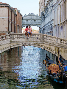 男女平等漫画摄影照片_一对男女在意大利威尼斯的城市旅行中坐在叹息桥的海滨