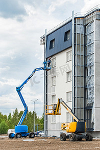 2020新高度摄影照片_白俄罗斯，明斯克 — 2020年5月28日：升降平台上的一名工人正在为建筑工地正在建设的一座新的现代城市建筑的正面涂漆
