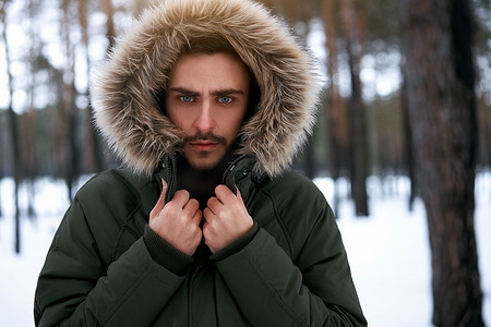 有魅力的大胡子男人站在冬季森林的户外。