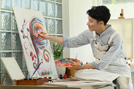 宜人的艺术家在画布上用水彩创作艺术品，在家里享受创意活动。