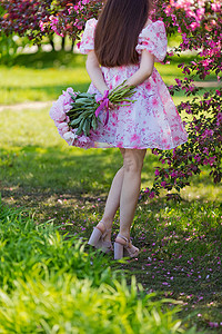 一个穿着粉红色连衣裙的女孩，手捧一大束牡丹，