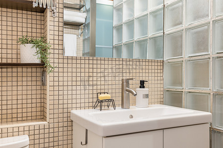 舒适的白色水槽，墙上挂着肥皂盘镜，时尚浴室的米色马赛克瓷砖上架着玻璃瓷砖。