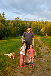 父亲带着孩子和狗在乡间小路上