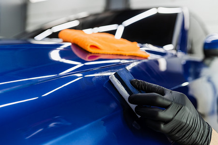 在汽车细节服务中使用海绵在车身上涂上陶瓷保护涂层的过程。