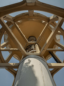 音量柱状摄影照片_由水泥和金属螺旋楼梯制成的柱状结构旧水塔的自下而上视图。