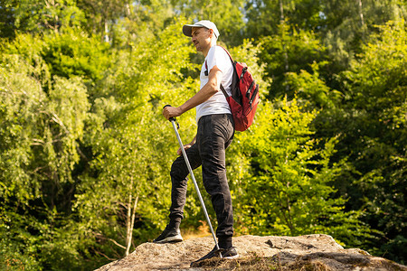 绿女孩摄影照片_男子手持登山杖，带有绿色散景背景和复制空间。
