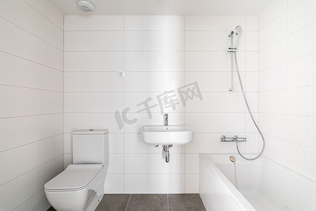 酒店或新公寓的现代浴室铺有白色米色瓷砖，配有梳妆台和开放式淋浴间。