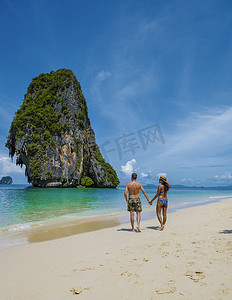 莱雷海滩甲米泰国，莱雷甲米热带海滩，海滩上的情侣男女，泰国田园诗般的莱雷海滩全景，乘坐传统的长船