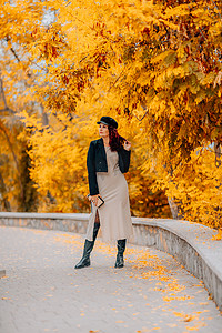 散步摄影照片_一个女人在秋天到户外散步，享受秋天的天气。