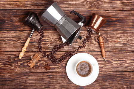 一杯咖啡，三个咖啡壶，肉桂，茴香，木制托盘上的咖啡豆。