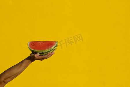 一个男人的手拿着一块西瓜