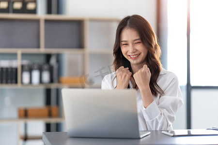美丽的学生摄影照片_美丽的亚洲女人使用笔记本电脑，激动和庆祝商业成功的好消息。
