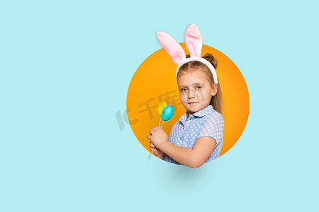 带着复活节兔耳朵的可爱小女孩拿着彩蛋