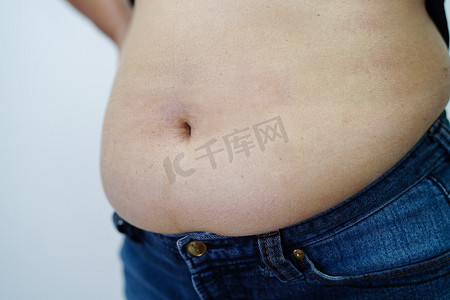 肥胖女性摄影照片_亚洲女性在办公室表现出肥胖的腹部大尺寸超重和肥胖。