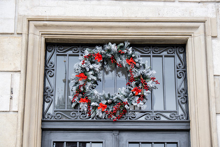 黑色木制前门上有红球和人造雪的绿色圣诞花环。