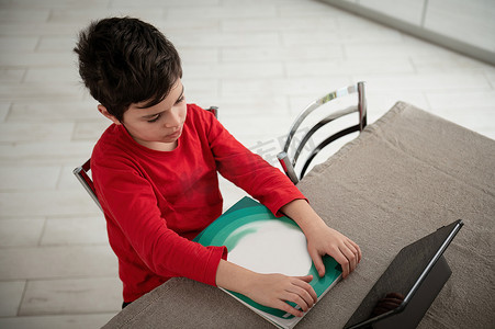 一个小学生做家庭作业，使用数字平板电脑学习的俯视图。
