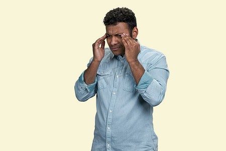 年轻的棕色印度男人因头痛或偏头痛而摸头。