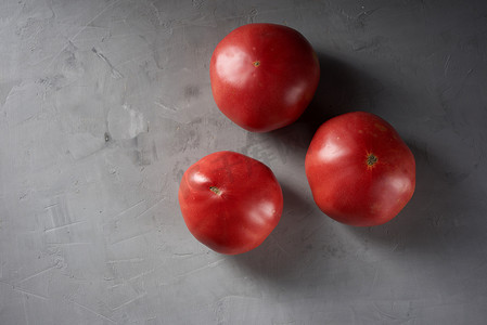 国画西红柿摄影照片_灰色背景中的三个熟红番茄，顶视图
