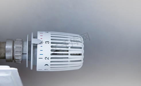 电池家在摄影照片_在白色散热器上用恒温器调节室内的加热电池温度。