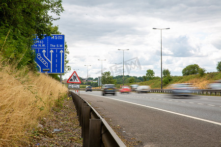 道路指示牌摄影照片_驶过英国高速公路标志的车辆