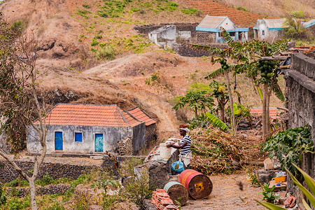 一名妇女在非洲佛得角圣地亚哥岛山区一座简陋房屋前工作