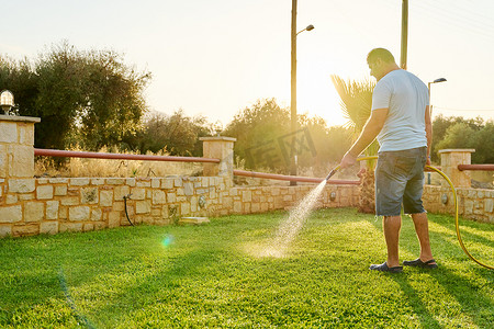男人早上用软管给草坪浇水