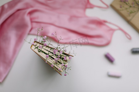 平躺组合物，带有优雅的粉红色连衣裙、书籍、白色背景顶视图上的花朵