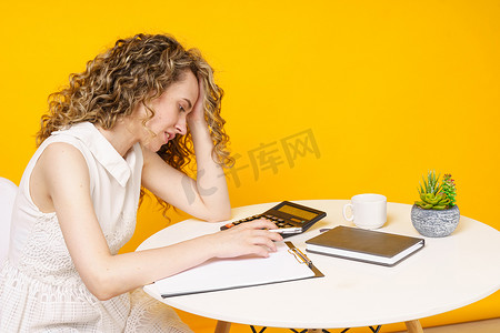 一名年轻女子坐在桌旁，处理文件，思考，研究。