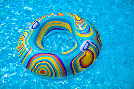 漂浮的紫色摄影照片_蓝色泳池中的彩色泳池漂浮