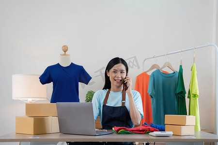 美丽的亚洲女性在线卖家通过电话确认客户的订单，创办小型企业的中小企业主女企业家在家里使用笔记本电脑、包装和交付情况概念。