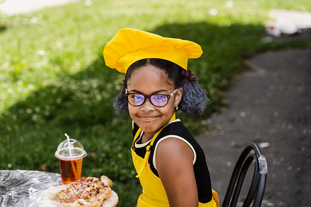 黑人非洲厨师女童罪孽厨师帽和黄色围裙制服在户外微笑。