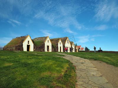 Glaumber 露天民俗博物馆传统的冰岛房屋，有草皮屋顶和墙壁，有绿草和蓝天，有一群游客