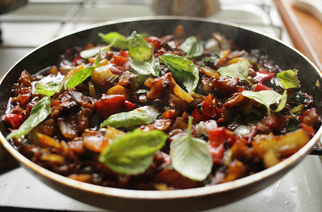 煎炸蒸烤摄影照片_健康食品蔬菜在平底锅中油炸番茄茄子洋葱胡椒西葫芦
