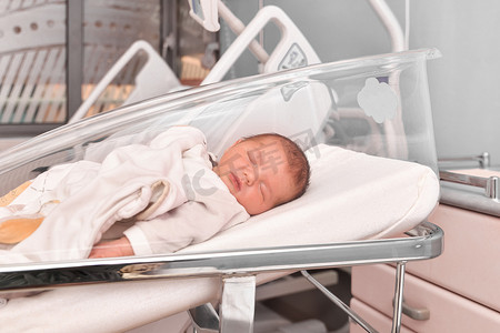 病床上摄影照片_睡觉在医院病床上的新出生的婴孩