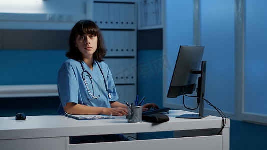 执业摄影照片_执业护士在医院办公室工作数小时同时输入医疗报告的肖像