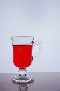 在白色背景光效果下将红色液体倒入玻璃杯中