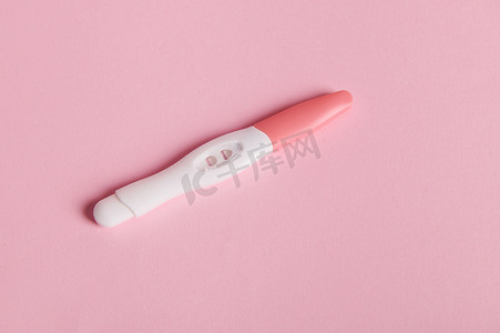 噴墨喷墨摄影照片_粉红色背景的阳性喷墨怀孕测试套件。