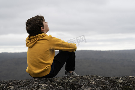 小孩眼睛摄影照片_侧视图 一个闭着眼睛坐在山顶呼吸新鲜空气的小孩的肖像