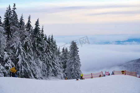 在德国 Hessen Rhoen 的 Wasserkuppe 山脉和天空的背景下，在云杉林中有滑雪场和滑雪缆车的冬季山脉全景。