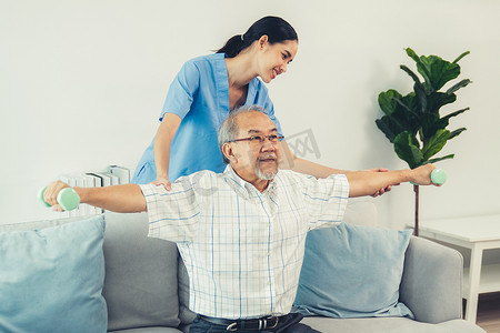 在护理人员的帮助下进行物理治疗的心满意足的老年患者。