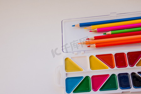 带彩色铅笔、画笔和水彩画的儿童书桌，带复制空间的顶视图。回到学校。绘图用品，各种彩色铅笔。教育框架概念。