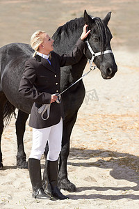 女子骑马摄影照片_骑马者、教练员和带宠物参加马术训练和比赛的女子。