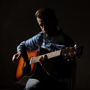 身穿格子衬衫的男子肖像弹奏着融合的电声吉他。