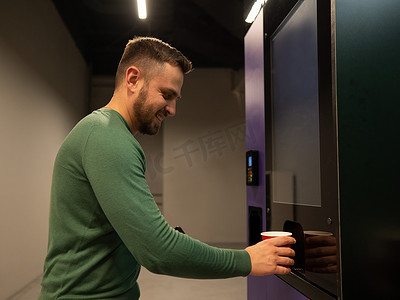 自动售货机矢量图摄影照片_白人男子从自动售货机给自己倒咖啡。